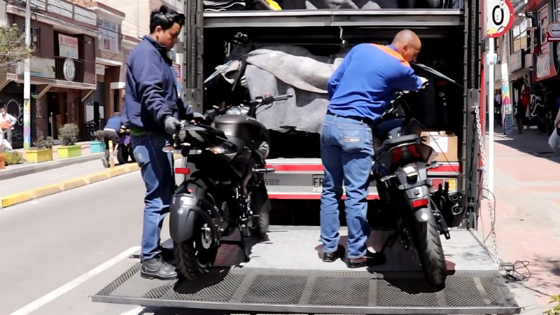 Personal operativo asegura motocicletas en camión de carga para su transporte seguro.