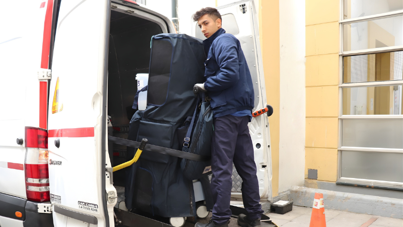 Colaborador de Transportes Clavijo descargando cuidadosamente un equipo médico desde un vehículo de transporte especializado frente a una institución de salud.